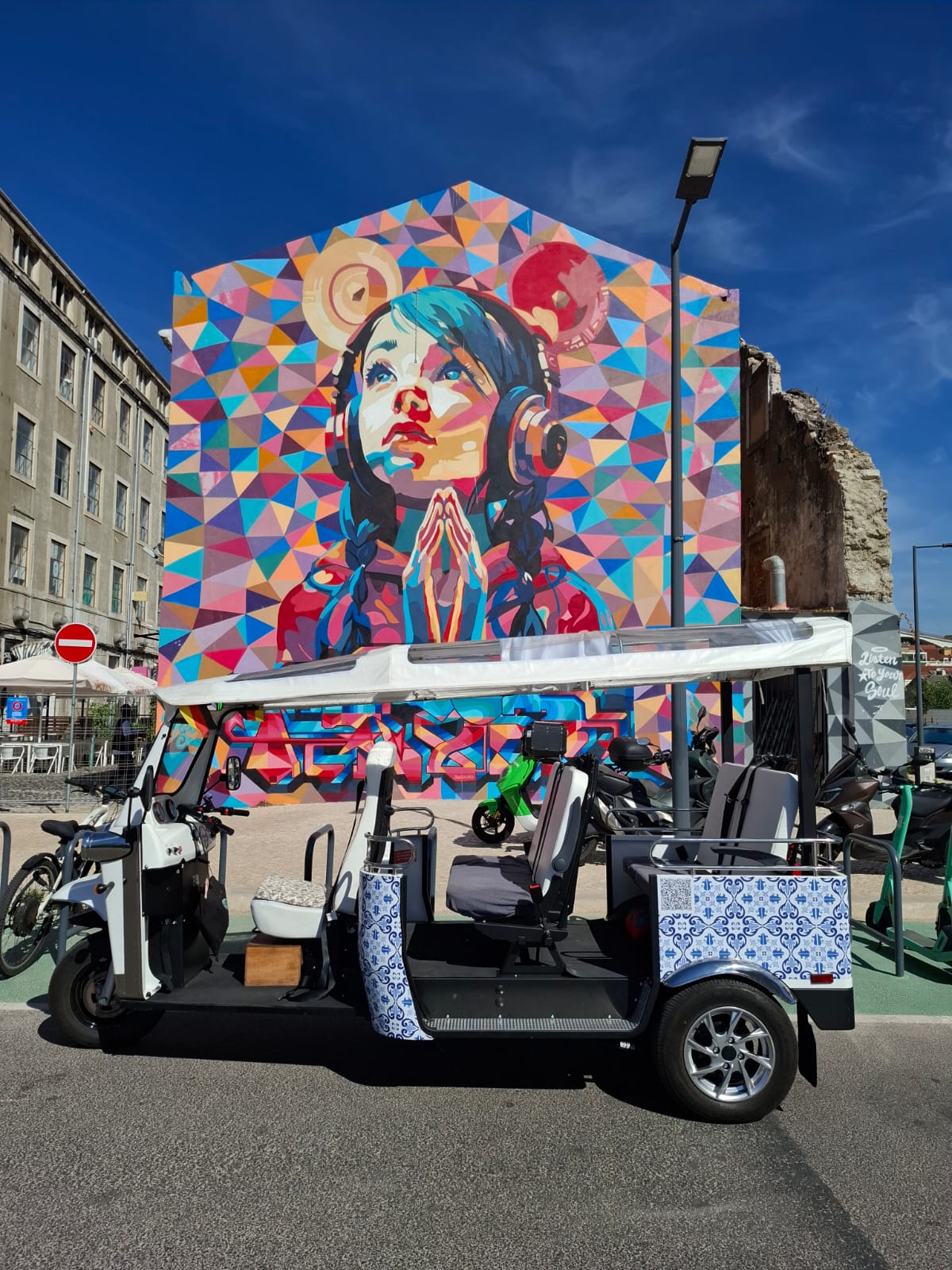 Street art Lisbon private tour — guests with Tukxi electric tuk tuk at a striking urban art installation