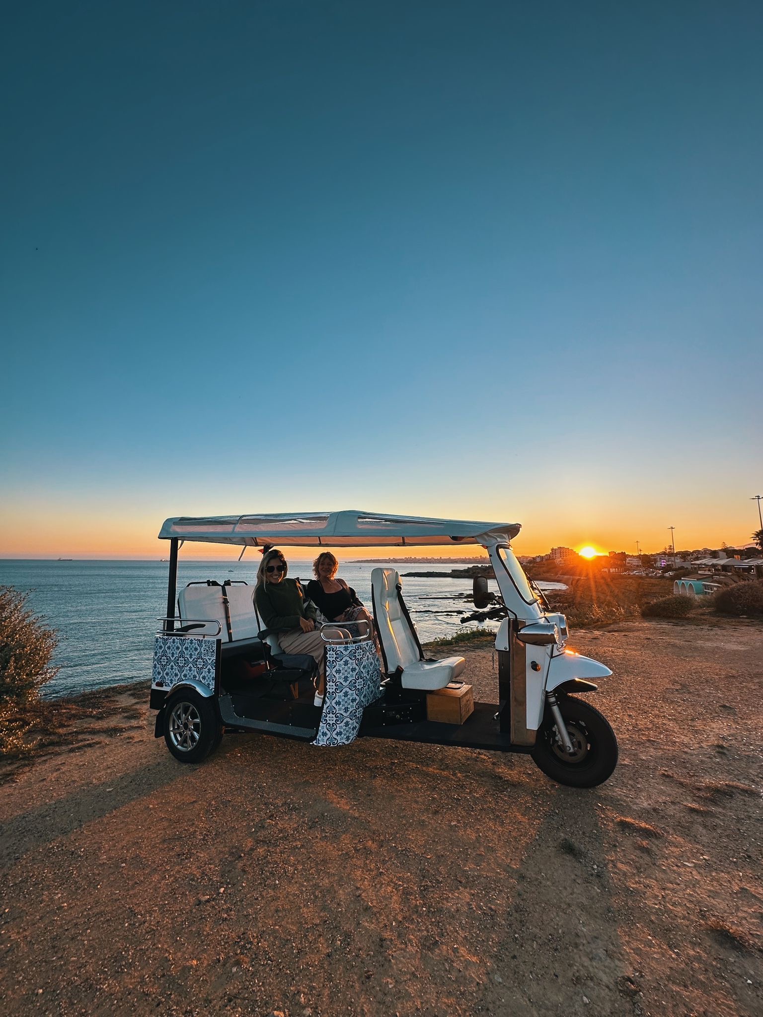 Tukxi private electric tuk tuk at golden hour Lisbon — Lisbon Sunset Tour with panoramic viewpoint in the background