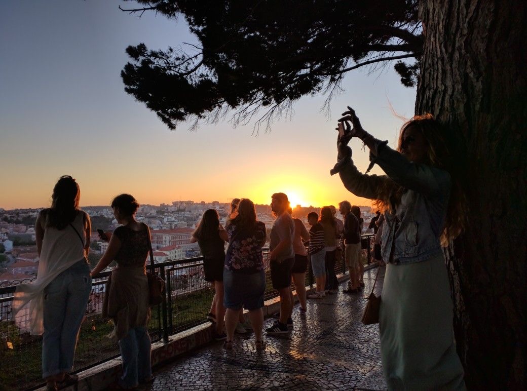 Guests in a Tukxi electric tuk tuk at a Lisbon sunset viewpoint — private golden hour tour through Alfama and the miradouros
