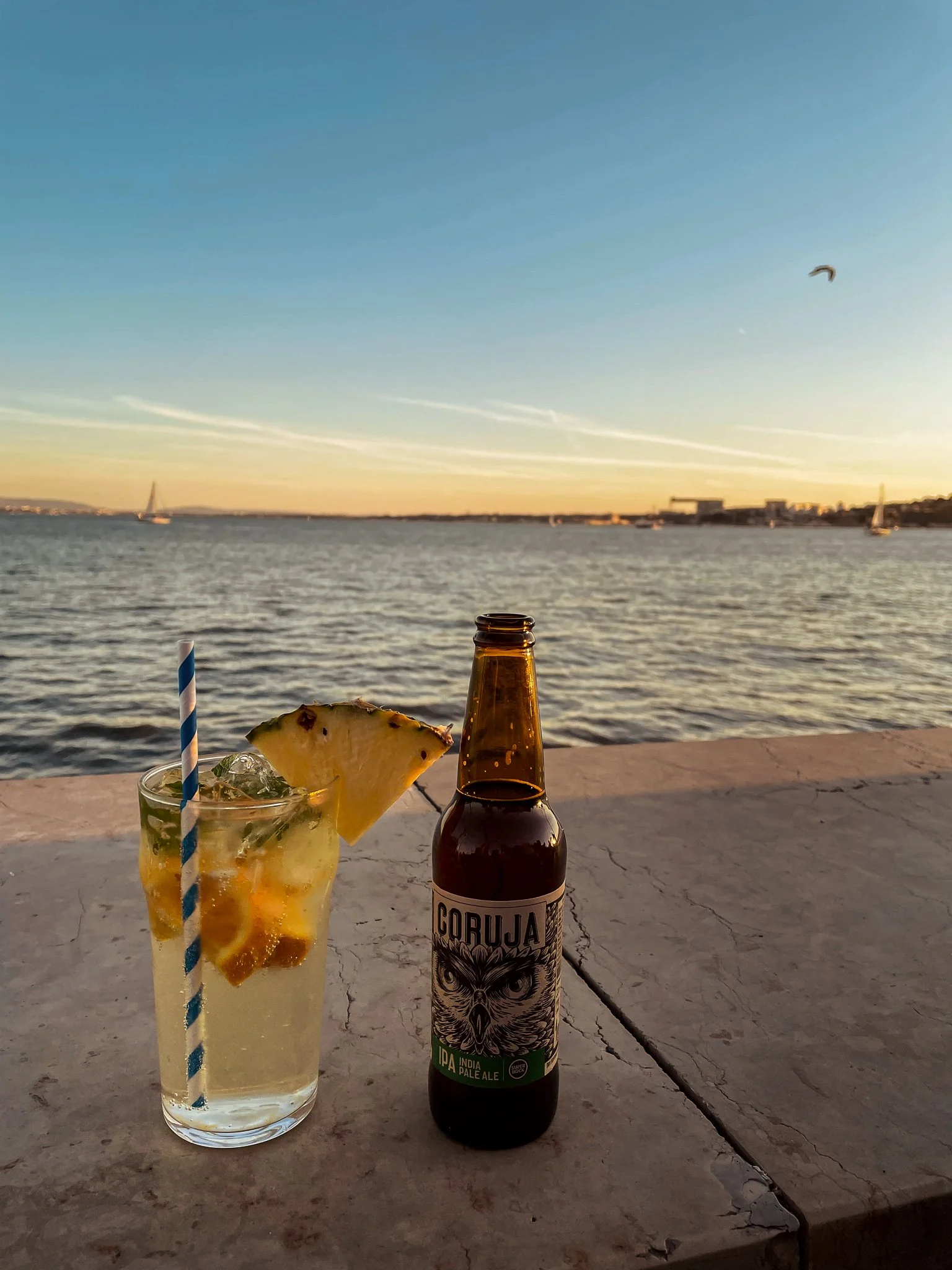 Lisbon sunset panorama from a rooftop terrace — golden light over the Alfama rooftops and the Tagus River estuary